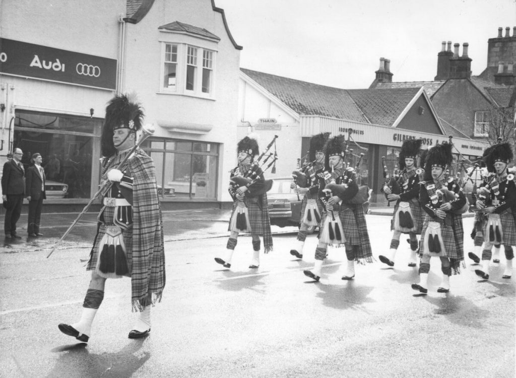 Invergordon Distillery Pipe Band marching down Invergordon High Street